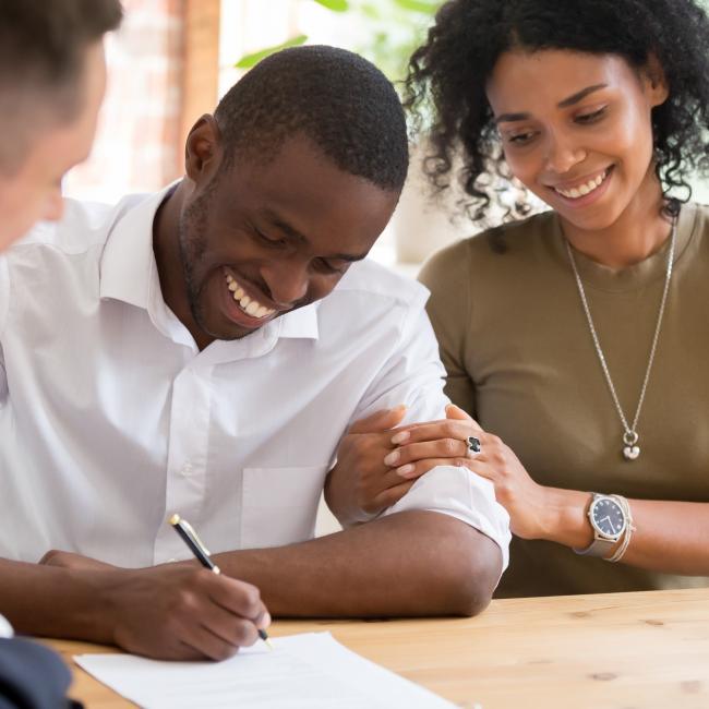 A couple sign for a home loan. 